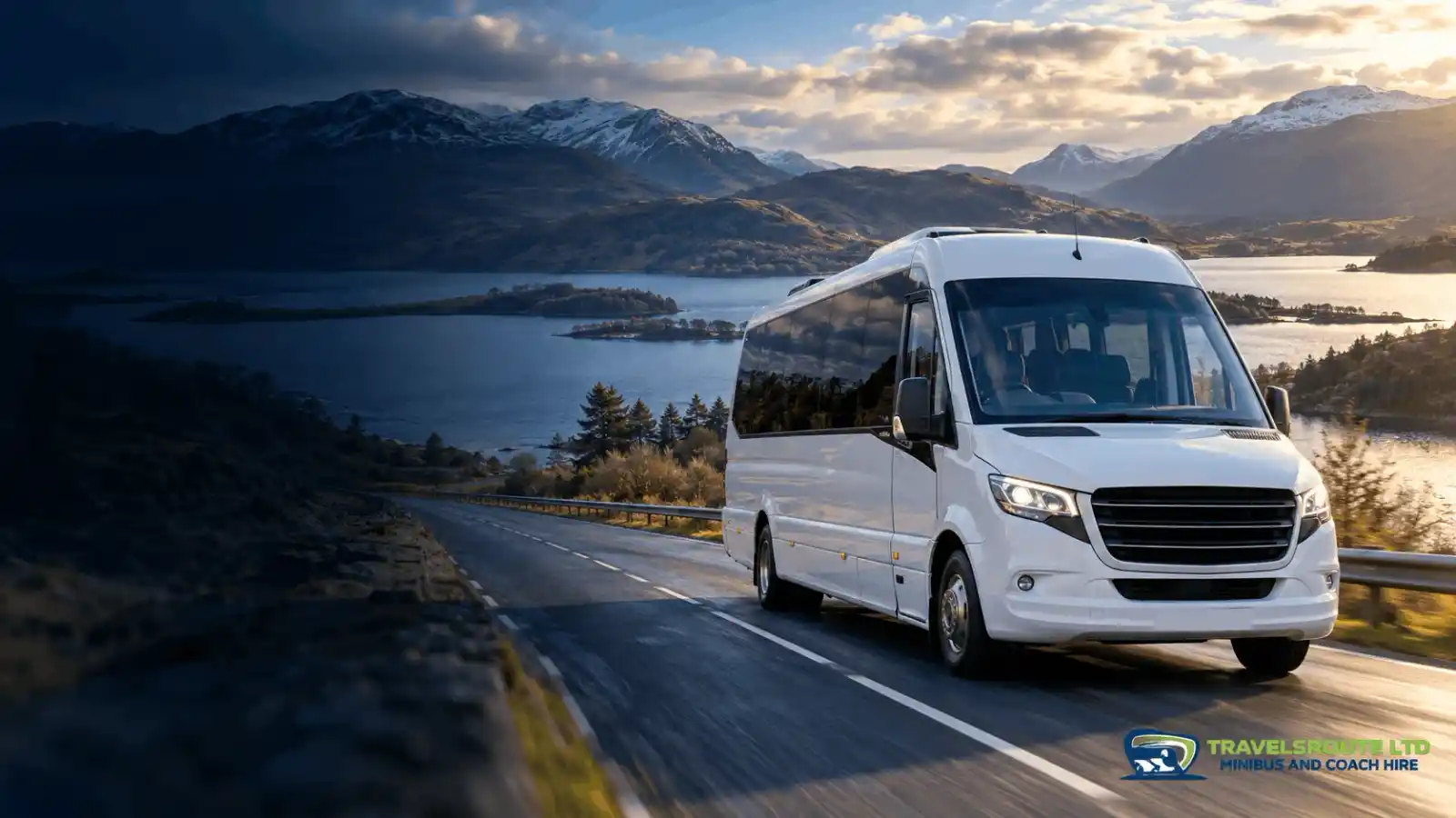 A TravelsRoute minibus on a Scottish Highlands road beside a loch and snow-capped mountains